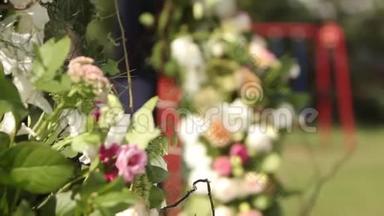 户外婚礼的婚礼装饰。 用白色和粉红色玫瑰装饰的木制拱门。 蜜蜂和大黄蜂